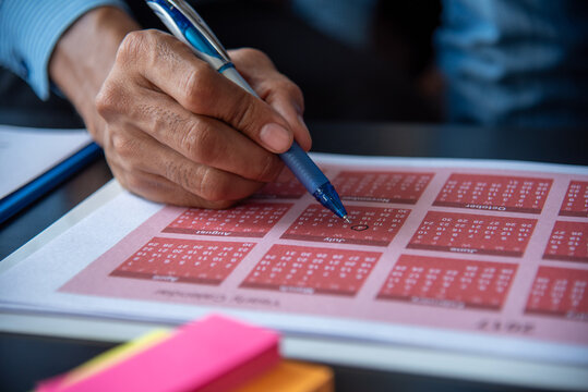 Calendar plan event. Close up man Hands using pen note 2027 event planner timetable agenda plan schedule event. Man planner agenda organizer schedule. 2026 Calendar desk objects on office table