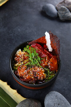 Traditional Hawaiian dish. Dark background. Poke with octopus, avocado, and tomatoes. Top view.Copy space