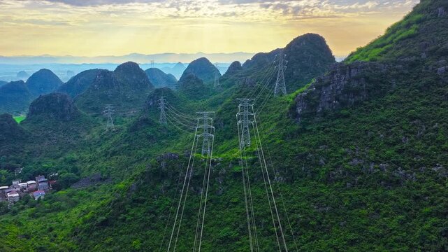 Karst mountains and limestone cliffs surround power transmission towers near Guilin, China, combining dramatic geological scenery with rural energy infrastructure.