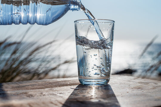 Glass of pure mineral water on wooden surface outdoors