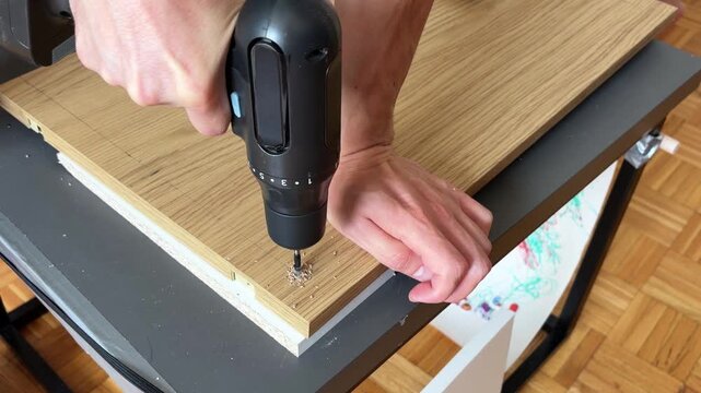 Close up of drilling pilot holes in wooden furniture panel during home assembly project