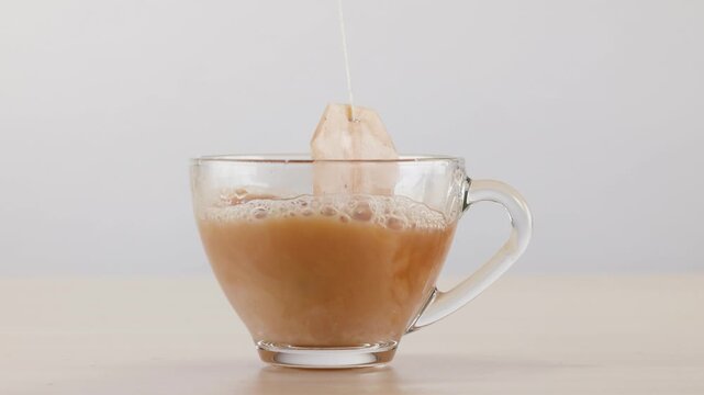 Tea Bag Steeping and Dipping in Glass Cup of Hot Water