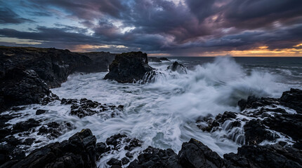 Fototapeta premium Sea waves crashing on volcanic rocks under stormy sunset sky