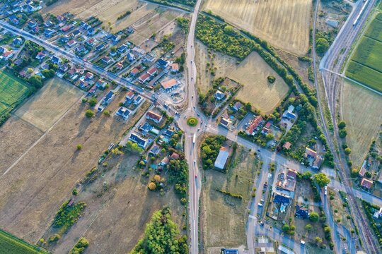 Aerial view of a roundabout in the town of Bantzenheim surrounded by residential houses and agricultural fields in Bantzenheim, Grand Est, France.