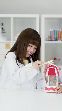 Young Girl in Lab Coat Brushing Large Dental Model