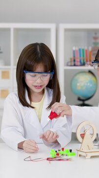 Young Girl in Lab Coat Performing Science Experiment in Classroom