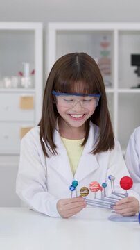 Elementary Student in Lab Coat Examining Solar System Model