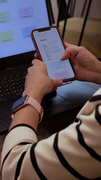 Professional reviewing and upgrading resume using AI tools on her phone and laptop. Woman using gadgets and AI assistant to proofreading her resume