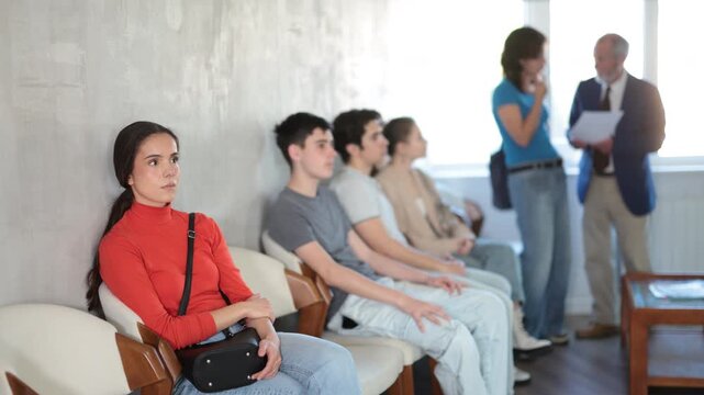 Queue of applicants is waiting in reception room, senior male manager talking to office-seeker in background. Job interview, labor policy, elimination of unemployment. 