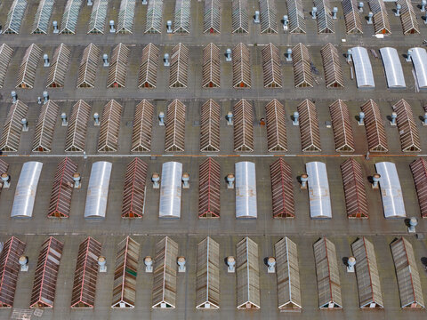 Aerial view of a large industrial warehouse roof featuring repetitive triangular skylights and ventilation units in Poland.