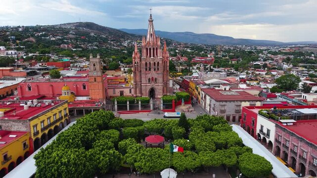 A breathtaking aerial panorama capturing the soaring neo-Gothic spires of the Parroquia de San Miguel Arc&aacute;ngel rising above the historic colonial cityscape.