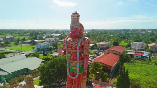 Aerial orbit around towering Hanuman Murti statue at Dattatreya Mandir temple reveals lush Trinidad countryside and temple grounds