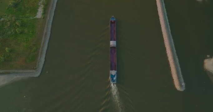 Top-down drone rise from a cargo ship reveals the expansive Dutch polder landscape, lined canal dikes and surrounding farmland, showcasing inland shipping and water management.