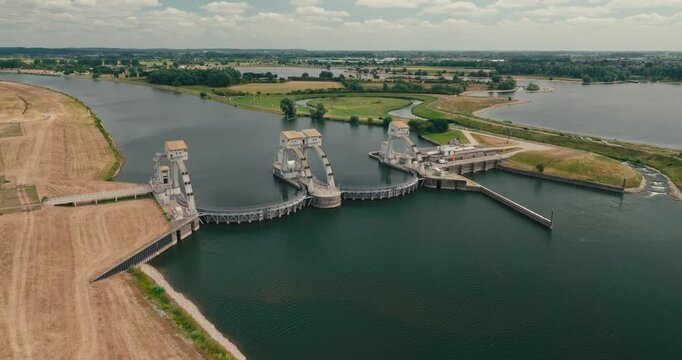 Drone approaches a hydroelectric power plant in a Dutch canal, revealing the visible water level difference and engineered structures regulating water flow and navigation.