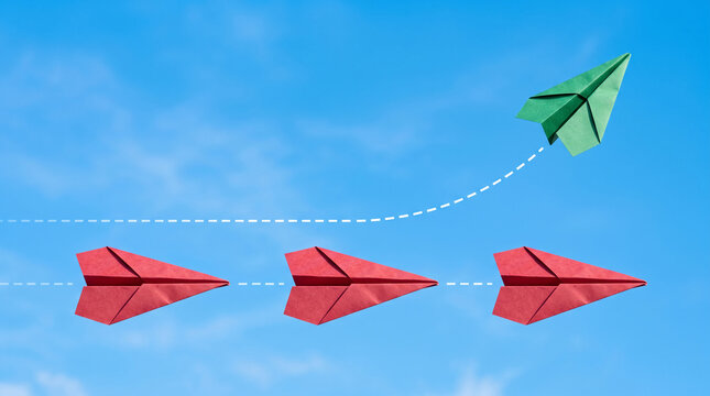 Red paper airplanes follow a dashed line, while a green one breaks away, symbolizing change, innovation, and individuality against a clear blue sky