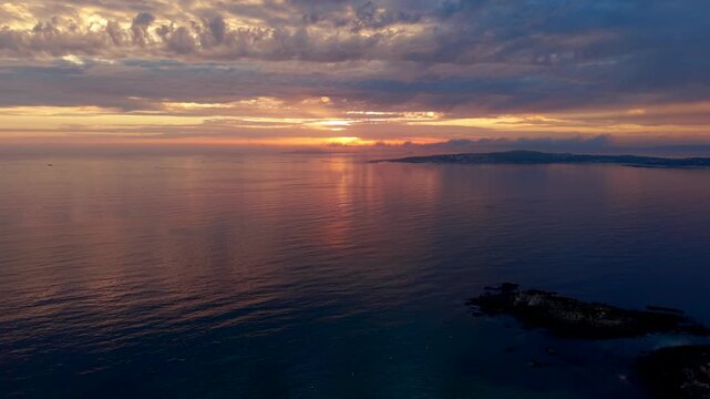 Aerial - Golden sunset light reflecting on calm sea near A Lanzada Beach Galicia Spain