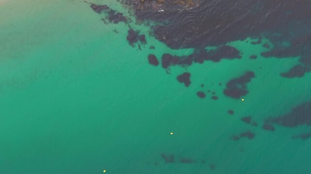 Aerial - Clear turquoise water over dark submerged rocks and seaweed beds in Sanxenxo Spain