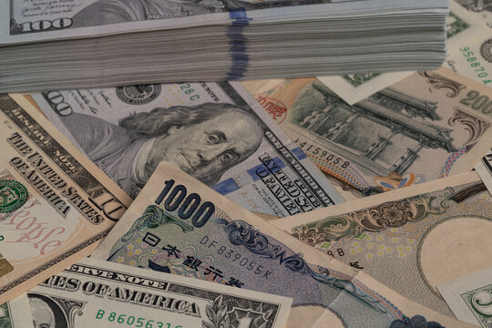 Japanese 1000 yen bill on top of stack of US 100 dollar banknotes background