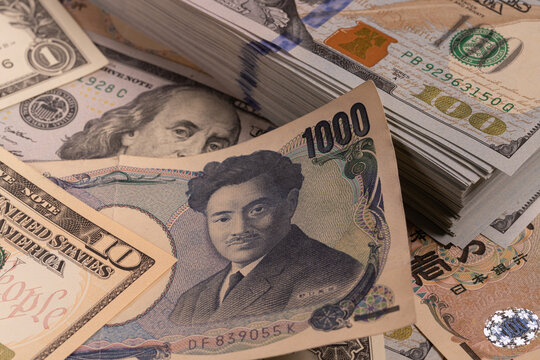 Japanese 1000 yen bill on top of stack of US 100 dollar banknotes background