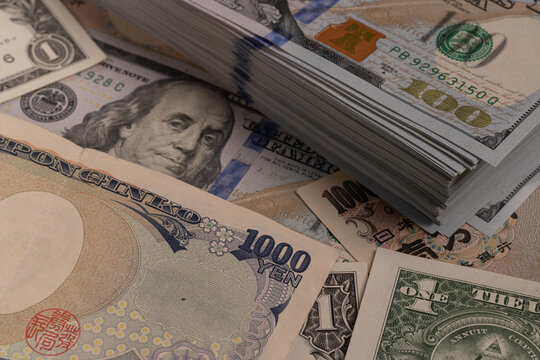 Japanese yen banknotes (1000, 2000, 10000) over stack of US dollar bills background