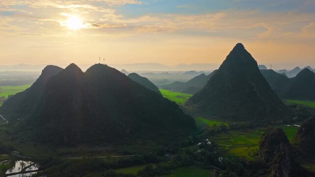 Sunrise illuminates Guilin karst peaks, green rice fields, winding waterways, and rural valley scenery in Guangxi, China, offering a travel and tourism background.
