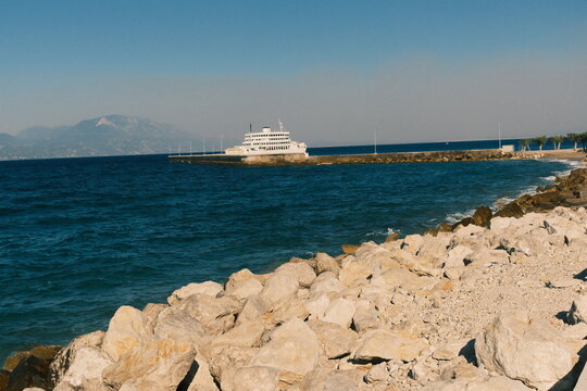 Ferry boat docked near rocky shoreline in open sea during clear daytime