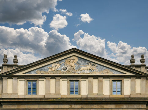Historic facade and decorated tympanum of the famous Teatro alla Scala opera house under a cloudy sky in Milan, Italy