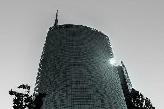 MILAN, ITALY - MAY 02, 2025: Low angle view of the modern UniCredit Tower skyscraper in black and white with sun reflection on glass facade.