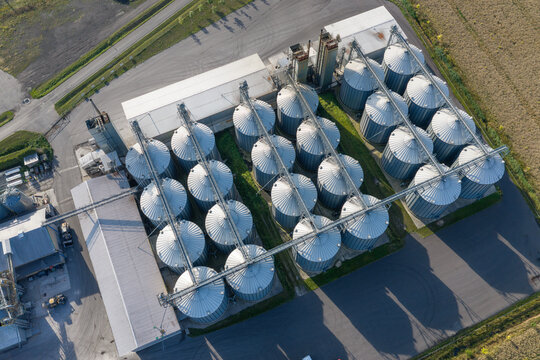 Aerial view of a modern feed production and grain procurement facility with rows of metallic silos, industrial infrastructure, and paved access roads in Poland.