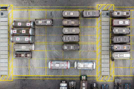Aerial view of tank containers arranged in a logistics yard with yellow safety markings on the asphalt in Poland.
