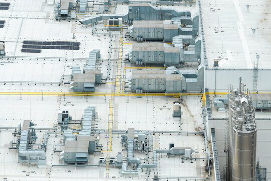 Aerial view of a food processing facility featuring industrial ventilation systems, HVAC units, and a large stainless steel silo on a flat roof in Poland.