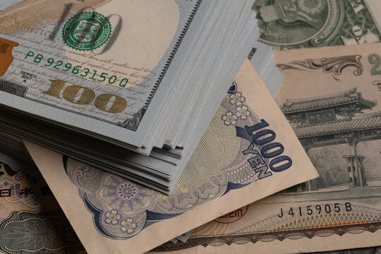 Japanese yen banknotes (1000, 2000, 10000) over stack of US dollar bills background