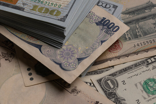 Japanese yen banknotes (1000, 2000, 10000) over stack of US dollar bills background