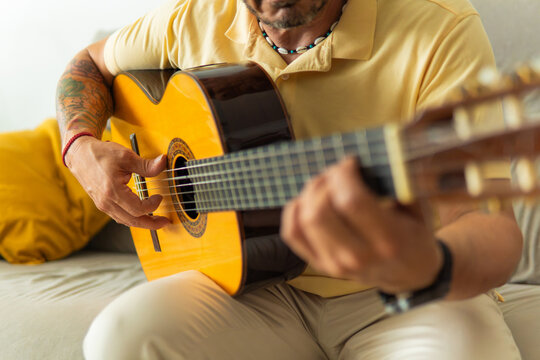 Man playing acoustic guitar at home enjoying leisure time