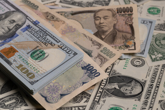 Japanese yen banknotes (1000, 2000, 10000) over stack of US dollar bills background