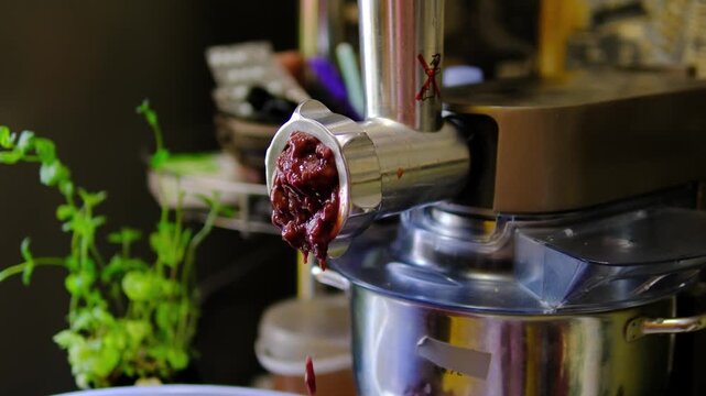 Grinding fresh beef liver through a meat grinder to make homemade liver mince for traditional recipes