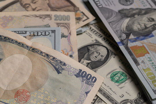 Japanese yen banknotes (1000, 2000, 10000) over stack of US dollar bills background