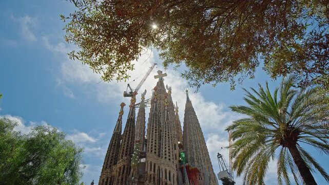 Sagrada Familia basilica framed by palm trees and Mediterranean vegetation in Barcelona Spain, iconic Gaudi architecture