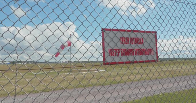 Windsock indicating wind direction on airfield runway under cloudy sky