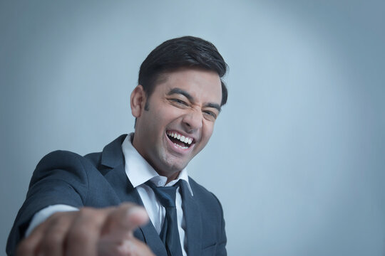 Young businessman smiling pointing at camera