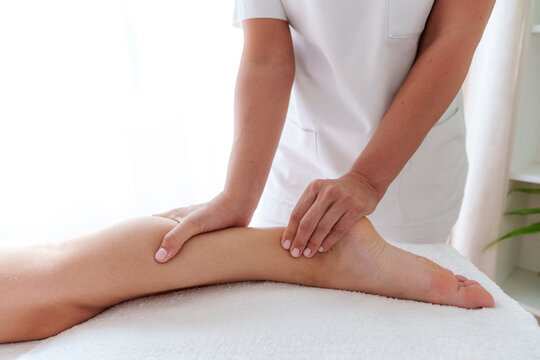 Osteopath massaging patient's calf in treatment room