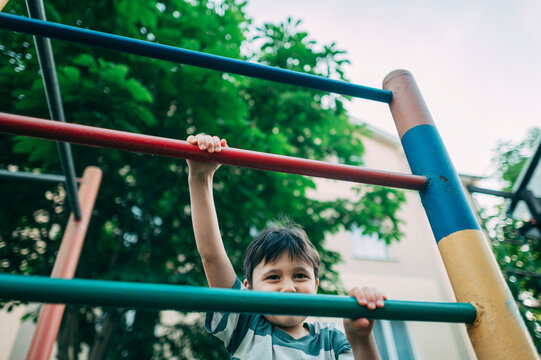 A happy boy climbs the jungle gym at the outdoor playground