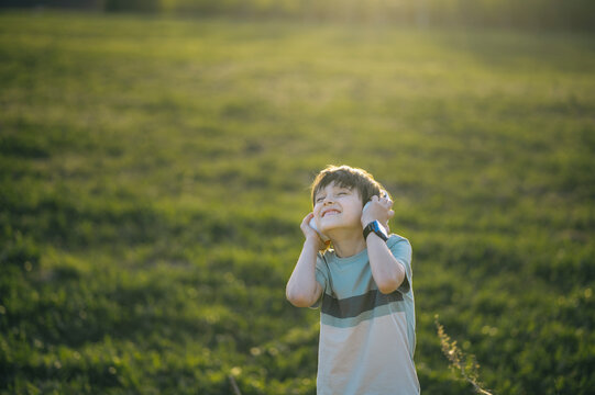 Music lover dancing and listening to audio in a field at sunset