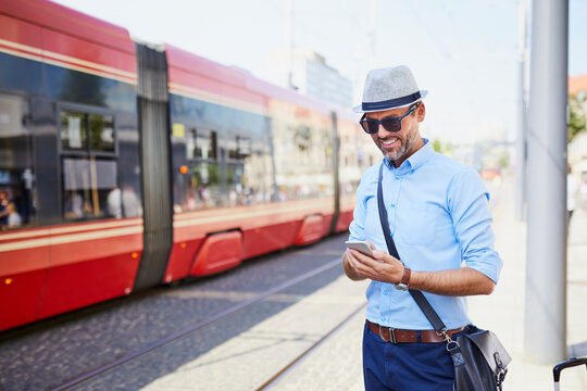 Traveler in the city using cell phone at tram stop