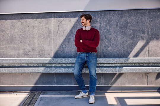 Relaxed commuter leaning against concrete wall in parking lot