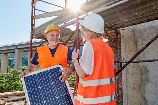 Man and woman discuss a solar panel at a construction site