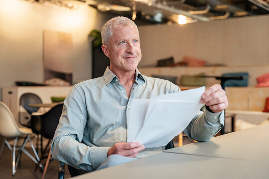 Thoughtful businessman reads document at the office desk