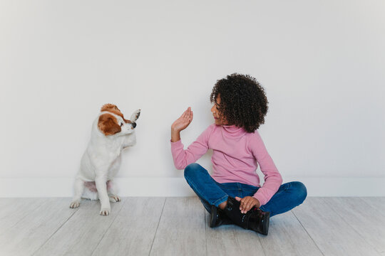 Little girl sitting on the floor playing with her dog