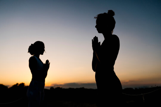 Silhouette of women in prayer position outdoors