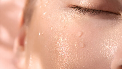 Fototapeta premium Extreme closeup of a persons face with water droplets on glowing, dewy skin